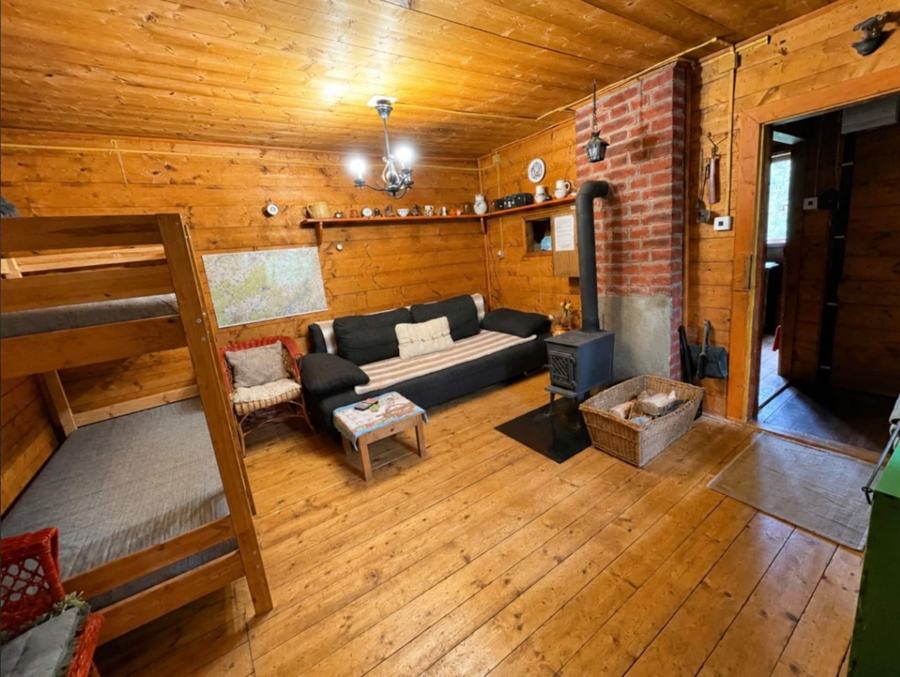 Dřevěný obývací prostor s gaučem, kamny a cihlovým komínem
