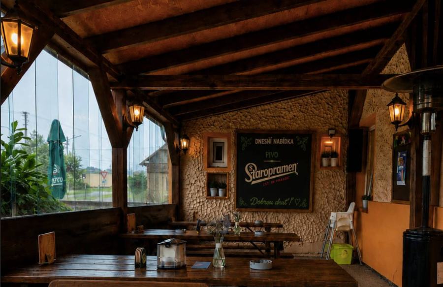 Krytá zahrádka restaurace s dřevěnými stoly